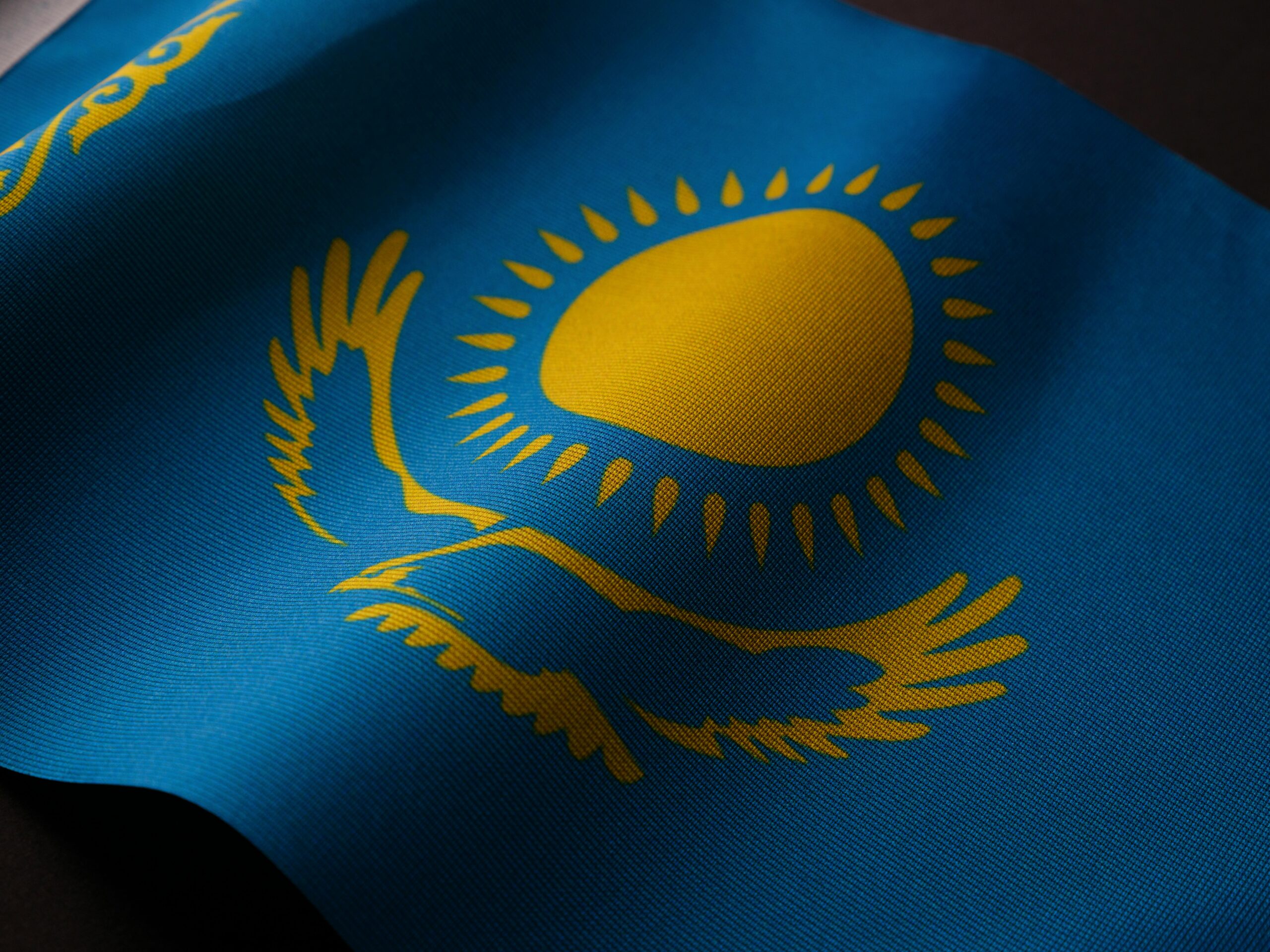 Close-up of the Kazakhstan flag featuring a golden sun and eagle on a blue backdrop.